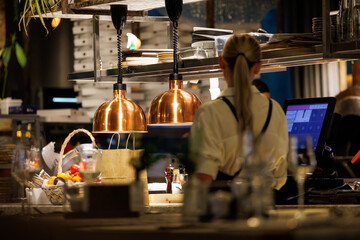 A chef is focused on preparing dishes in a lively restaurant kitchen, showcasing modern decor and ingredients.