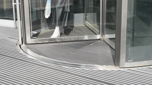 business center in big city, central entrance with revolving door, people come in and go out, modern architecture, urban background
