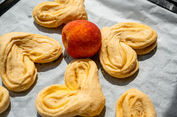 Raw buns on a baking tray with parchment paper
