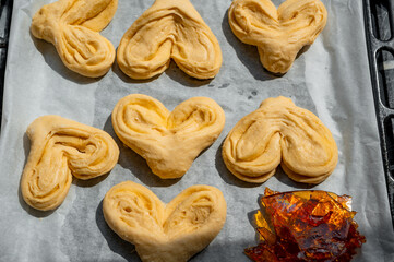 Unbaked sweet buns placed on a baking tray next to a sheet of brown caramel. Concept of high-sugar and high-carbohydrate homemade pastries and desserts.