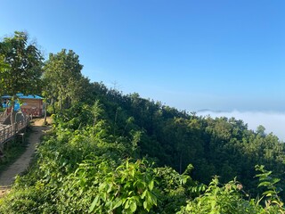 hills with beautiful clouds in the morning. Summer Mountain with green plants and clouds in the sky. wooden hut on Mountain. Texture of green tree forest view from above, Beautiful sunrise.