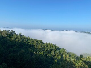 hills with beautiful clouds in the morning. Summer Mountain with green plants and clouds in the sky. wooden hut on Mountain. Texture of green tree forest view from above, Beautiful sunrise.