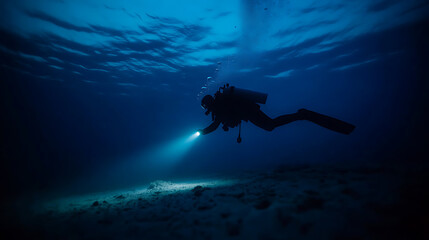 Fototapeta premium A lone scuba diver navigates the deep ocean, torchlight cutting through the darkness, revealing the sandy seabed below. Underwater exploration is very cool.