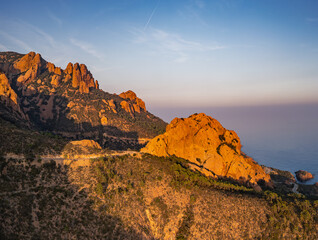 Obraz premium Aerial view of Esterel Mountains and winding coastal road above the blue Mediterranean Sea, French Riviera, France