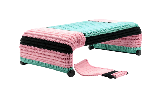 A low rectangular stool with colorful knitted panels and a detached section, set against black
