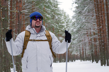 Man enjoying cross-country skiing in winter forest landscape