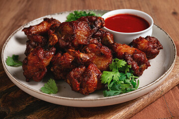 Juicy fried chicken pieces, served with spicy dipping sauce, on a rustic wooden table,