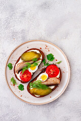 sandwiches on rye bread, with sprats, quail eggs, fresh tomatoes and pickled cucumber, appetizer, breakfast, homemade,