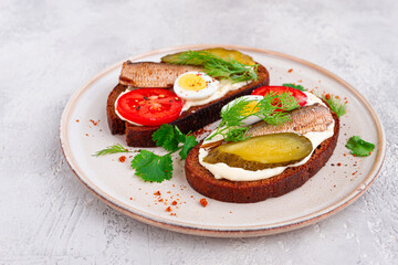 sandwiches on rye bread, with sprats, quail eggs, fresh tomatoes and pickled cucumber, appetizer, breakfast, homemade,