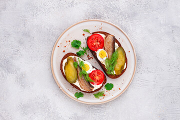 sandwiches on rye bread, with sprats, quail eggs, fresh tomatoes and pickled cucumber, appetizer, breakfast, homemade,