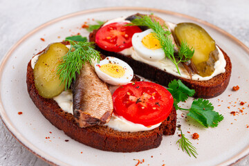 sandwiches on rye bread, with sprats, quail eggs, fresh tomatoes and pickled cucumber, appetizer, breakfast, homemade,