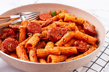 rigatoni pasta with spicy sausage, and rich tomato sauce served, on a white plate, homemade,