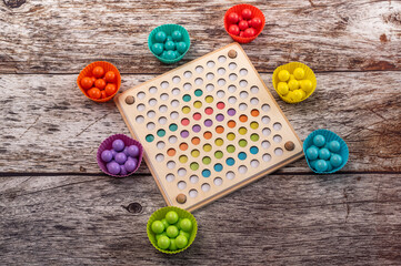 Wooden Montessori educational toy with multicolored spheres for preschool motor training. Sorting board helping children enhance sensory development and color coordination.