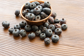 Close-Up of Wild Blueberries in a Copper Bowl on a Wooden Surface

