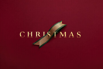 Stylish burgundy Christmas background featuring gold typography crossed by gold-green ribbon. Clean luxury flat lay with generous copy space. Minimalist Banners, website headers, posters brand design.