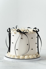 Delicate lambeth style birthday cake with white cream cheese frosting decorated with cream tracery and black happy birthday text on top. White background