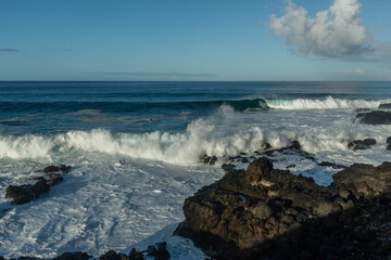 Scenic vista of waves breaking against the rocky shore along the Kaena Point trail on Oahu, Hawaii