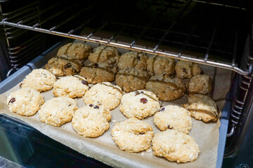 Freshly baked ANZAC biscuits on parchment paper and a baking tray, just out of the oven.