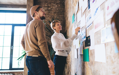 Freelancer duo celebrates project milestone with high five in front of UX board, expressing success...