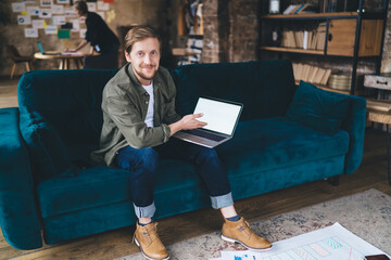 Freelancer confidently showcases blank laptop screen, offering space for digital branding, UI...