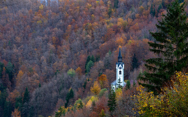 Scenic view of a church nestled among autumn trees in the mountains during golden hour