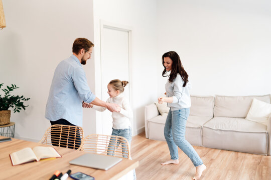 Family dances barefoot in living room, joyful break from digital life, showing playful bond, emotional connection and conscious detachment from devices. - Powered by Adobe