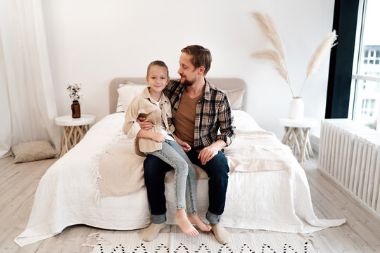 Father embraces daughter on bed, both smiling gently, illustrating warmth, emotional security, and parent-child bonding in soft digital family setting.