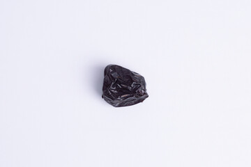 Single Ajwa date, flat lay, isolated on a clean white background. Symbolizes healthy Iftar food, Ramadan blessing, sweet energy, and luxury desert fruit snack.
