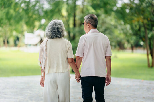Senior man woman walking holding hands outdoors tranquil park healthy lifestyle retirement happiness