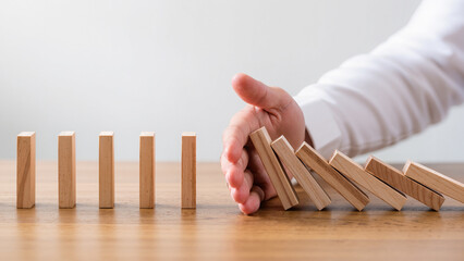 Businessman hand stop falling down of wood block. planning and strategy business disruption concept