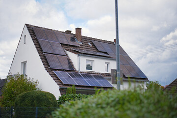 Solar panels on modern family house roof, sustainable residential building with renewable energy system, eco-friendly electricity generation, suburban neighborhood in Europe