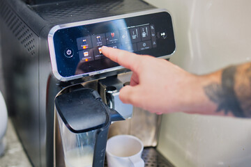 Close-up of a Hand Selecting Latte Macchiato on Touchscreen Coffee Machine Interface in Modern Kitchen Setting