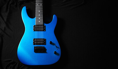 Fototapeta premium Blue electric guitar on black background, close-up of strings, pickups and bridge, music instrument concept for rock and studio design.