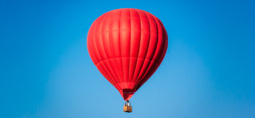 Obraz premium Red balloon in the sky. Aerostat. People in the basket. Fun. Summer entertainment. Romantic adventures.