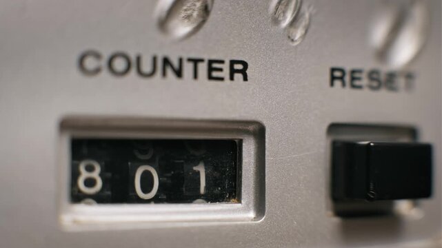 Close-up of a mechanical counter on a vintage device as the numbers roll over from 799 to 800. The white digits on the black wheels continue to advance sequentially on the silver equipment face.