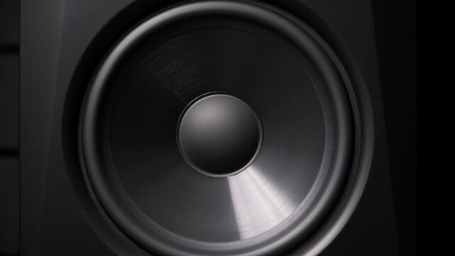 Extreme close-up of a black speaker cone vibrating from intense bass frequencies. The flexible membrane moves with powerful low-end sound waves in a dark audio environment.