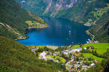 Geiranger village and Geirangerfjord surrounded by steep mountains and deep blue water in Norway