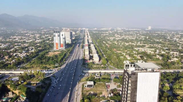 Wide Aerial Panorama of a Major City Avenue, Modern Buildings, and Mountains on a Clear Day