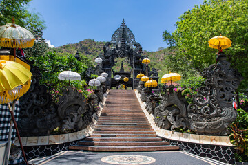 Explore the stunning Balinese temple gateway adorned with vibrant umbrellas, perfect for travel...