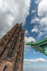 Ancient and impressive view of Strasbourg Cathedral with famous iron gargoyle in foreground under cloudy sky