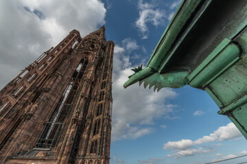 Ancient and impressive view of Strasbourg Cathedral with famous iron gargoyle in foreground under cloudy sky