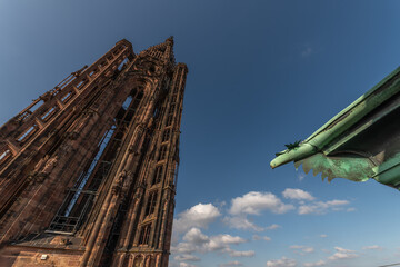 Ancient and impressive view of Strasbourg Cathedral with famous iron gargoyle in foreground under cloudy sky