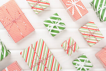 Obraz premium Many striped Christmas gift boxes on wooden background, top view