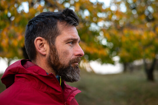 Pensive Bearded Man in Red Jacket Walking Outdoors in Autumn Nature - Powered by Adobe