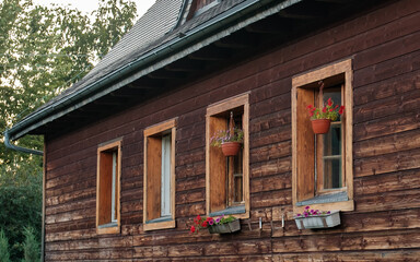 drewniany dom wiejski lub góralski z ciemnych, poziomych bali. Na ścianie znajdują się cztery okna o prostych, drewnianych ramach © PIOTR D