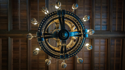 duży, okrągły żyrandol w stylu retro lub industrialnym, widziany z perspektywy z dołu, pod kątem prostym do sufitu