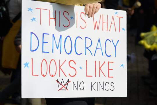 Protest sign "THIS IS WHAT DEMOCRACY LOOKS LIKE" with "NO KINGS"
