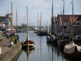 Picturesque Dutch canal with traditional wooden sailboats, gabled brick houses, cobblestone...