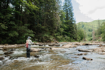 Fisherman catching trout in a mountain river