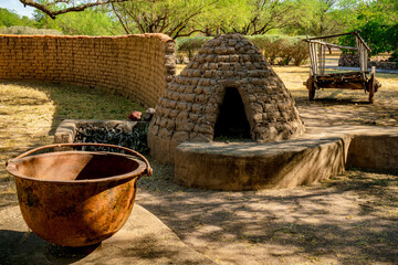 Large cast iron pot, kiva, and wooden horse drawn cart in a park in Tubac Arizona